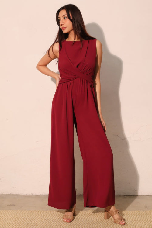 Woman wearing LuxeHaven™ red textured twist front jumpsuit with wide-leg silhouette on a plain background.
