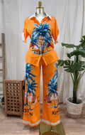 LuxeHaven™ women’s tropical two-piece set featuring palm print button-up top, wide-leg pants, and lightweight flowy fabric for effortless vacation styling.
