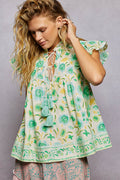 LuxeHaven floral tassel tie blouse for women featuring flutter sleeves, lightweight cotton fabric, a relaxed fit, and feminine boho-inspired floral styling.